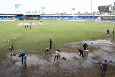 Ground staff try to clear the outfield at the Sharjah Cricket Stadium following heavy rainfall. Pawan Singh / The National
