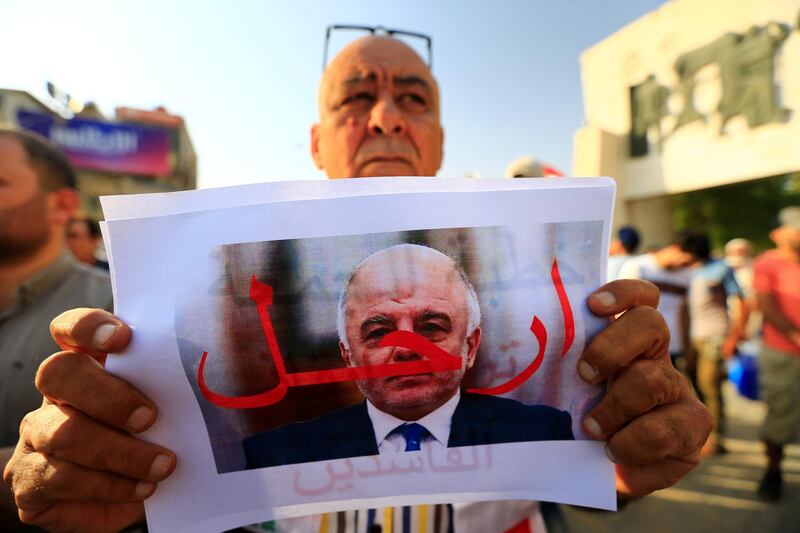 A protester holds a picture of Iraqi Prime Minister Haider al-Abadi with "Step Down" written on it during a protest at Tahrir square in Baghdad, Iraq July 27, 2018. REUTERS/Thaier al-Sudani