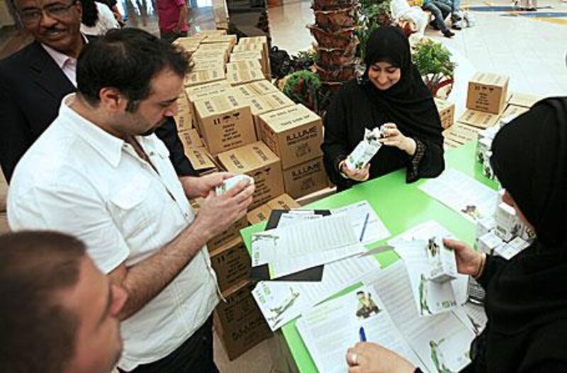 Sumaya al Obadilidli, right, gives out one of 40,000 energy-saving light bulbs at Marina Mall.