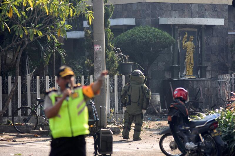 A member of the police bomb squad unit examines the site of an explosion outside the Immaculate Santa Maria Catholic Church, in Surabaya, East Java, Indonesia. Reuters