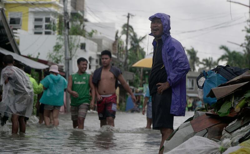 Residents wade from floodwaters in a flooded village in Sorsogon province. AP