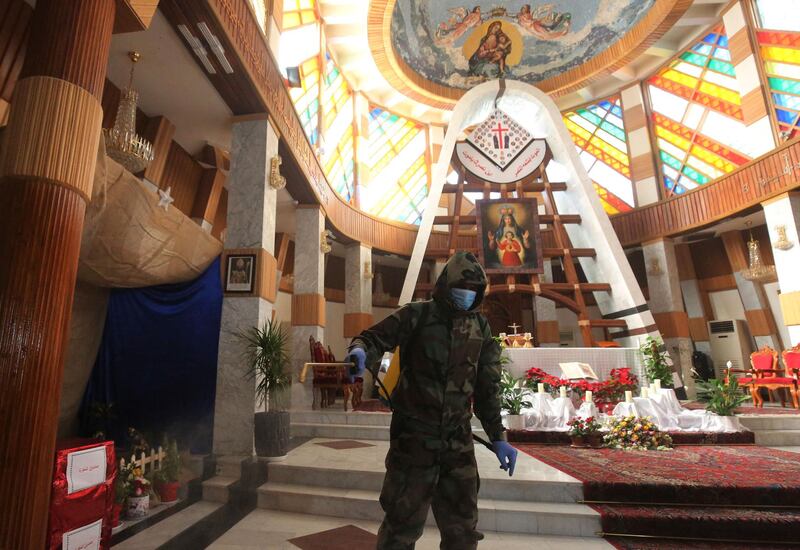 Iraqi members of a civil defence team disinfect the Our Lady of Salvation church in central Baghdad on December 30, 2020 amid measures to contain the spread of the Covid-19 coronavirus. (Photo by AHMAD AL-RUBAYE / AFP)