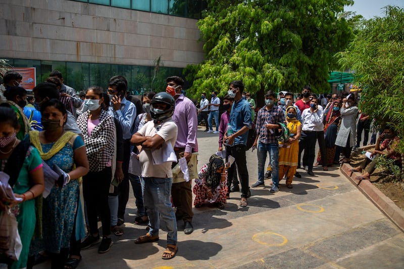 People wait for a Covid-19 test at a government hospital in Noida, a suburb of New Delhi, India. India reported more than 200,000 new coronavirus cases on Thursday, skyrocketing past 14 million overall as an intensifying outbreak puts a grim weight on its fragile health care system. AP Photo