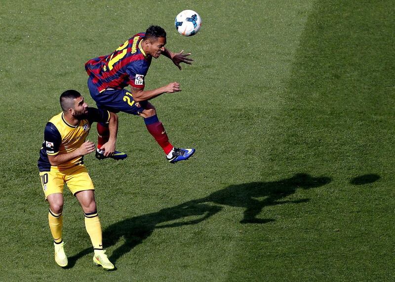 Barcelona defender Adriano, top, heads the ball over Atletico Madrid midfielder Arda Turan, left, during their La Liga match at the Camp Nou on Saturday. Alberto Estevez / EPA / May 17, 2014