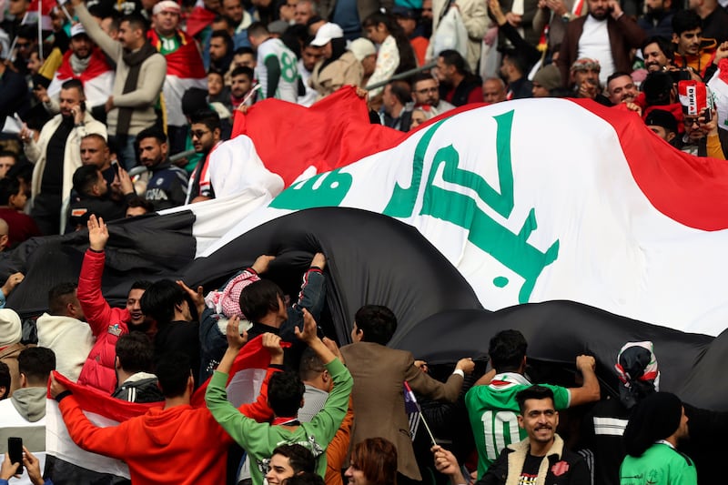 Fans cheering Iraq players with a huge flag at the semi-finals between Iraq and Qatar at Basra International Stadium. AP