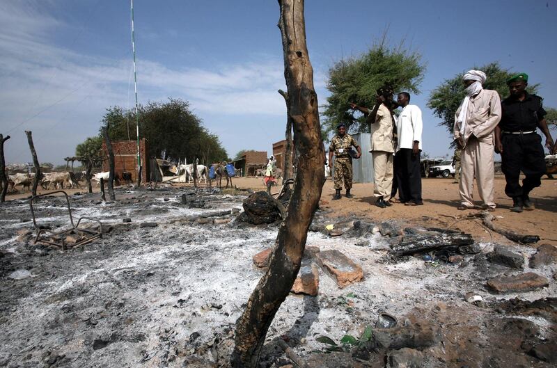 An African Union Mission in the Sudan (AMIS) military observer (L) and Sudan Liberation Army (SLA) members survey the burnt-out marketplace in Muhajariya town in southern Darfur, 10 October 2007, following violent clashes. The town, which is a stronghold of the SLA Minni Minnawi faction, the only rebel group to sign the May 2006 Darfur Peace Agreement, experienced heavy fighting 09 October in what the SLA said was a Sudanese government-backed attack in which more than 50 people died. The clashes left many homes burnt to the ground and shops destroyed and looted. The UN said 10 October that fighting had erupted elsewhere in Darfur between the SLA and the Sudanese army. AFP PHOTO/HO/AMIS/STUART PRICE. (Photo by AMIS / AFP)