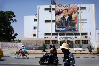 Local residents walk past revolutionary graffiti and a poster showing Mohammad Bouazizi in downtown Sidi Bouzid, Tunisia. Photo: Lindsay Mackenzie for The National.