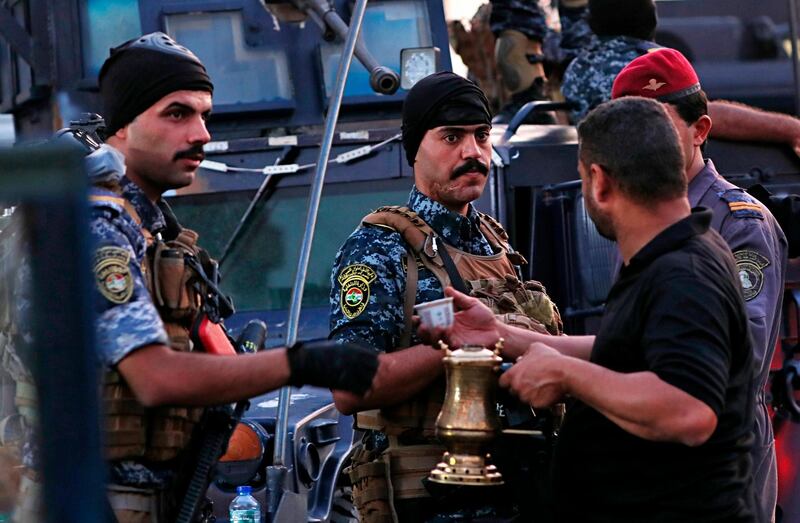 A street vendor sells coffee to members of the Iraqi Federal police as they deployed in Sadr City, Baghdad, Iraq. Iraq's prime minister on Monday ordered the police to replace the army in Sadr City, a heavily populated Shiite neighborhood of Baghdad where dozens of people were killed or wounded in weekend clashes stemming from anti-government protests. AP Photo