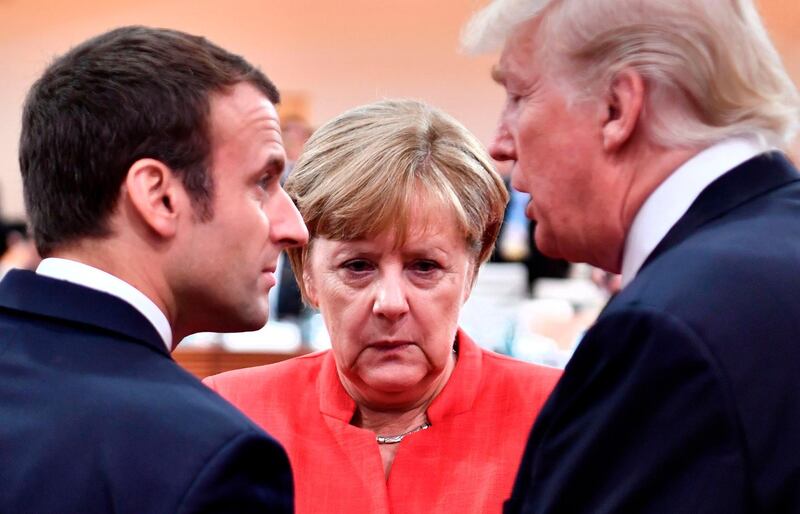 (FILES) In this file photo taken on July 7, 2017 (L-R) French President Emmanuel Macron, German Chancellor Angela Merkel and US President Donald Trump confer at the start of the first working session of the G20 meeting in Hamburg, northern Germany.
A year after his march to power, French President Emmanuel Macron's reformist zeal has endeared him to part of the electorate but polls show him as still unloved by most of the country.  Macron suffered a sharp drop in popularity when he began to push through changes to labour law last September that make hiring and firing easier.
 / AFP PHOTO / AFP PHOTO AND POOL / John MACDOUGALL