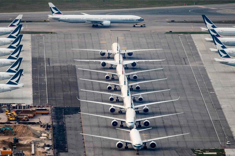 (FILES) In this file photograph taken on March 10, 2020, a Cathay Pacific passenger aircraft (TOP) taxis onto a runway as other aircraft belonging to the local flagship carrier are seen parked on the tarmac at Hong Kong's Chek Lap Kok International Airport.  Global air traffic will not return to levels seen before the coronavirus pandemic until at least 2024, the International Air Transport Association said on July 28, 2020. Uncertainty about the timing of border reopenings is the main factor, IATA's chief economist Brian Pearce told a news conference.
 / AFP / Anthony WALLACE
