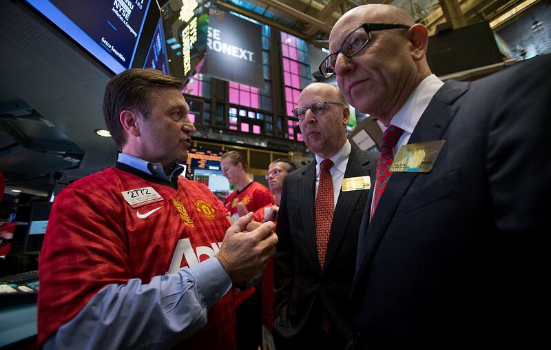 A trader wearing a Manchester United shirt speaks with Avram and Joel Glazer at the New York Stock Exchange in 2012