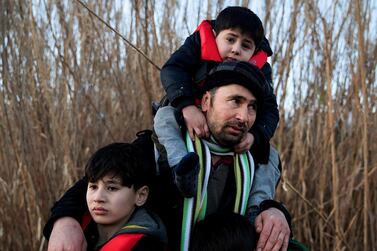 A man holds his three sons as migrants from Afghanistan arrive on a dinghy on a beach near the village of Skala Sikamias, after crossing part of the Aegean Sea from Turkey to the island of Lesbos, Greece, March 2, 2020. REUTERS/Alkis Konstantinidis TPX IMAGES OF THE DAY