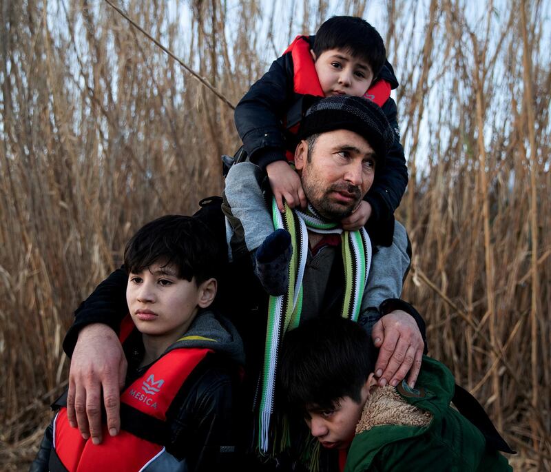 A man holds his three sons as migrants from Afghanistan arrive on a dinghy on a beach near the village of Skala Sikamias, after crossing part of the Aegean Sea from Turkey to the island of Lesbos, Greece, March 2, 2020. REUTERS/Alkis Konstantinidis     TPX IMAGES OF THE DAY