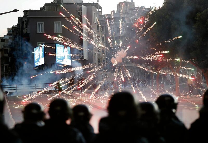 Supporters of the Shiite Hezbollah and Amal Movement groups, background, launch firecrackers at riot policemen as they try to attack anti-government protesters. AP