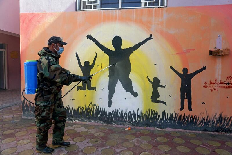 A member of the civil defense team disinfects a mural to prevent the spread of the coronavirus disease (COVID-19) at a school, in the holy city of Najaf, Iraq, February 8, 2021. REUTERS/Alaa Al-Marjani