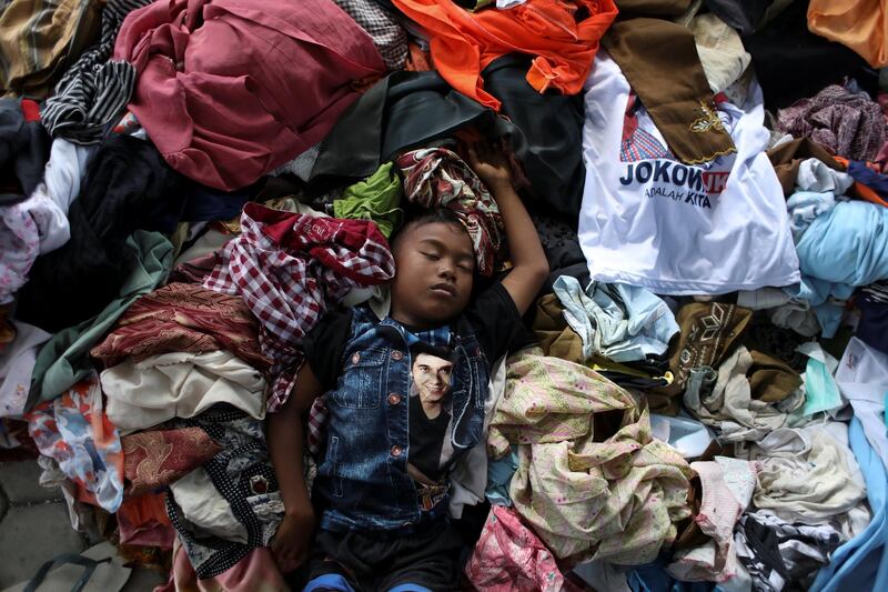 A boy sleeps over a pile of recycled clothes at a camp for displaced victims of the earthquake and tsunami in Palu, Central Sulawesi, Indonesia. Jorge Silva/Reuters
