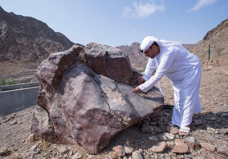 Sharjah, United Arab Emirates-  Abdullah Khilfan Al Naqbi showing early writings in a hill written on a big rock at Al Nahwa Village in Sharjah.  Leslie Pableo for The National for Ruba Haza