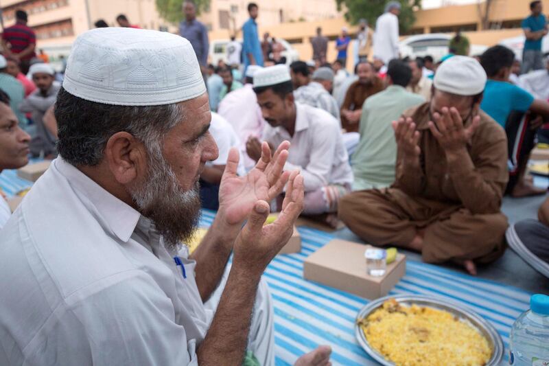 DUBAI, UNITED ARAB EMIRATES -  Some workers praying before breaking their fast.  Dubai Police join hands with Berkeley Assets to serve up Iftar dinner to mark Laylatul Qadr for 10,000 labourers with seating for 5,000 and another 5,000 laborers will go home with meal boxes in Al Muhaisnah, Dubai.  Ruel Pableo for The National