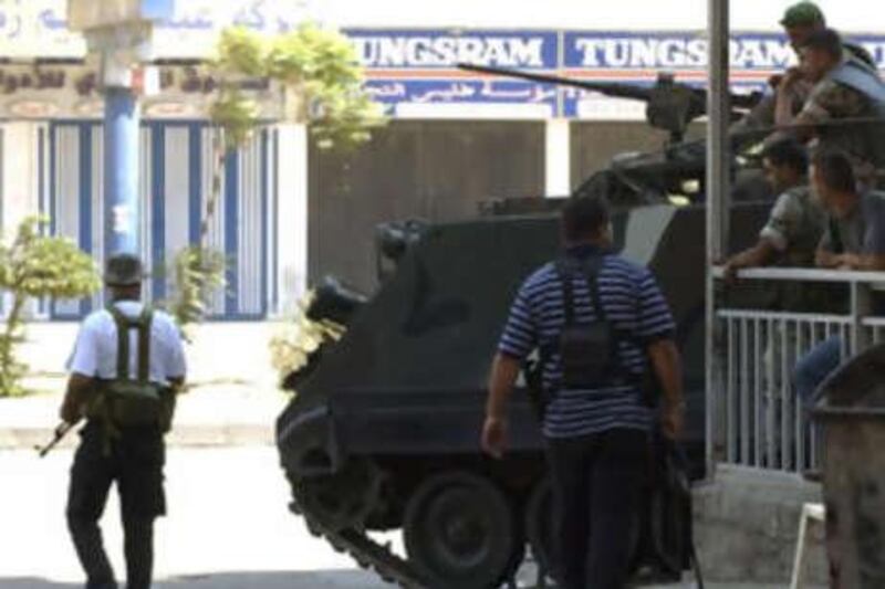 Gunmen walk past Lebanese soldiers on armoured personnel carriers in the Bab Tibbaneh district area during clashes between supporters of the government and Alawite gunmen close to the Hizbollah-led opposition in Tripoli.