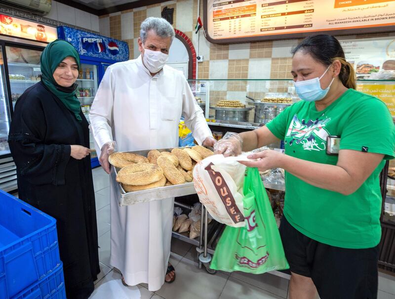 Abu Dhabi, United Arab Emirates, January 10, 2021.  Saeed Yousef Mardi and wife Arwa Mohamed Abib of Al Yousuf Sweets and Bakeries have a chat with some customers before giving them bread.
Victor Besa/The National
Section:  NA
Reporter:  Shireena Al Nowais