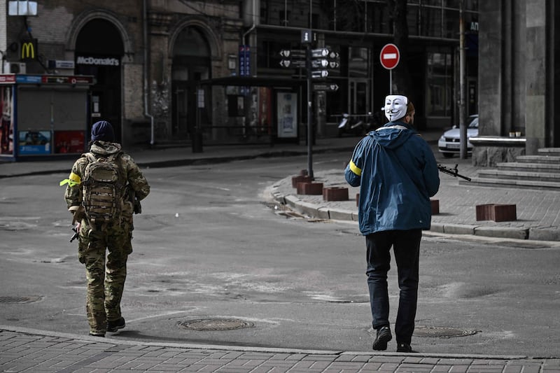 A member of the Ukrainian forces, wearing the Guy Fawkes mask popularised by Anonymous, patrols central Kiev. AFP