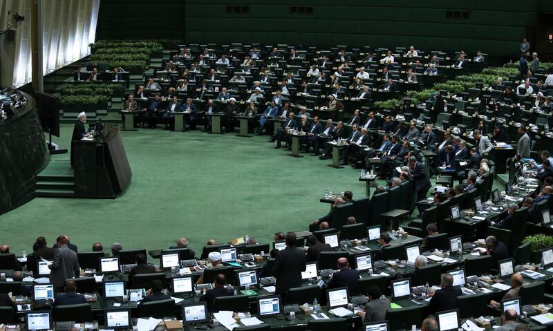 Iranian President Hassan Rouhani, left, speaks in a session of the parliament while answering questions of lawmakers, in Tehran, Iran, Tuesday, Aug. 28, 2018. Rouhani failed to convince parliament on Tuesday that his plans will pull the country out of an economic nosedive worsened by America's withdrawal from the nuclear deal, further isolating his relatively moderate administration amid nationwide anger. (AP Photo/Vahid Salemi)