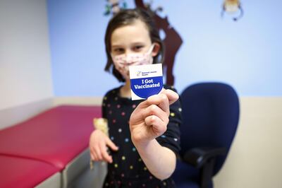 A seven-year-old girl holds out a sticker after receiving a dose of the paediatric Covid-19 vaccine in Denver, Colorado. Michael Ciaglo / Getty / AFP
