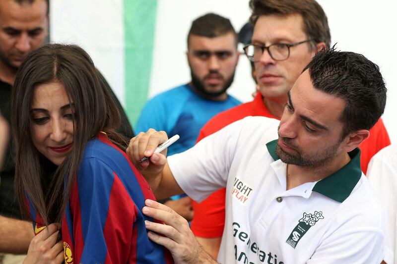 Former Barcelona football player Xavi Hernández, who now plays for Al-Sadd in the Qatar Stars League, signs a Barcelona shirt as he visits the Al Baqaa Palestinian refugee camp near Amman, Jordan, on September 29, 2016. Khalil Mazraawi / Agence France-Presse
