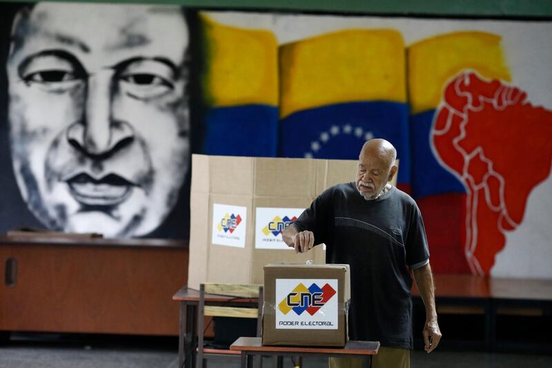 With an image of the late Venezuelan President Hugo Chavez behind him a Venezuelan citizen casts his vote at a polling station during the presidential election in Caracas, Venezuela. Marco Bello / Reuters
