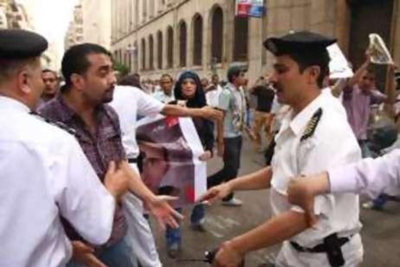 Egyptian policemen confront a demonstrator during a rally in support of slain 28-year-old Khaled Said in Cairo, Egypt Sunday, June 20, 2010, after the police allegedly  beat Khaled, a young businessman, to death on an Alexandria street after he posted a video on the Internet of officers sharing the spoils from a drug bust among themselves, his family said. (AP Photo/Ahmed Gomaa)          *** Local Caption ***  AMR103_Mideast_Egypt_Police_Beating.jpg