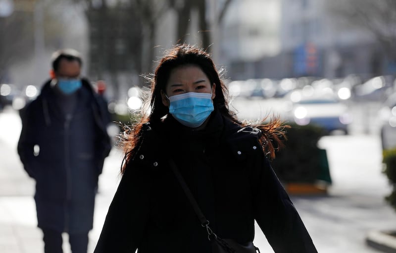A woman wearing a face mask walks along a street, following new cases of the coronavirus disease (COVID-19) in the country, in Beijing, China January 11, 2021. REUTERS/Tingshu Wang