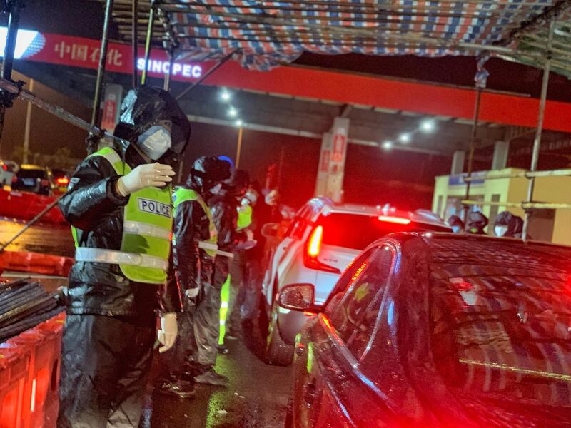 Police officers carry out information registration and temperature measurement for passing passengers at Jintang Island high-speed toll station in Zhoushan, Zhejiang Province, China.  EPA