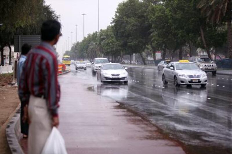 ABU DHABI, UNITED ARAB EMIRATES, April 28, 2013. Commuters wait at a bustop shortly after a heavy rain shower on Airport Road (2nd Street). The country has seen an unusually high level of rainfall of late. ( PAUL O DRISCOLL / The National )