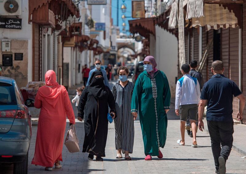 Pedestrians, wearing protective masks due to the pandemic, walk past closed shops in the Moroccan capital Rabat.  AFP