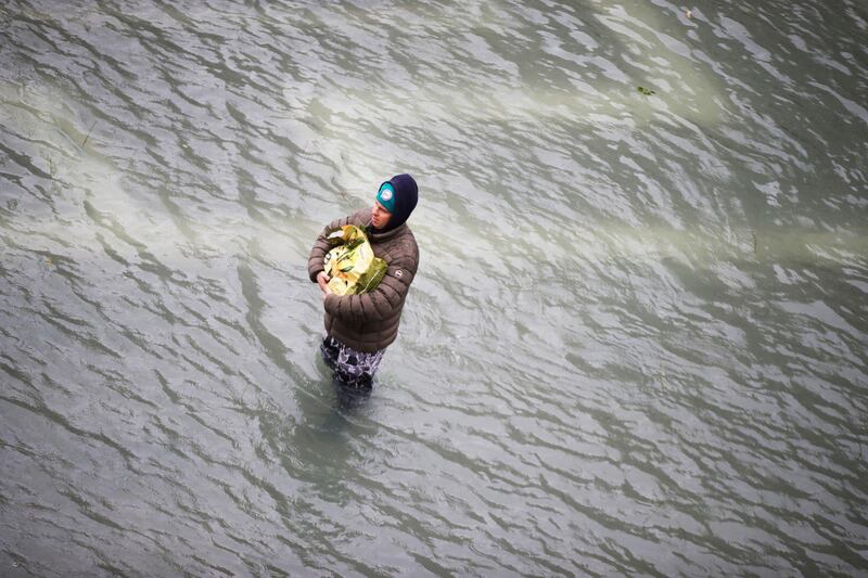 A man holds his bag as he stands in a flooded St. Mark's Square in Venice, Italy, Friday, Nov. 15, 2019. The high-water mark hit 187 centimeters (74 inches) late Tuesday, Nov. 12, 2019, meaning more than 85% of the city was flooded. The highest level ever recorded was 194 centimeters (76 inches) during infamous flooding in 1966. AP Photo