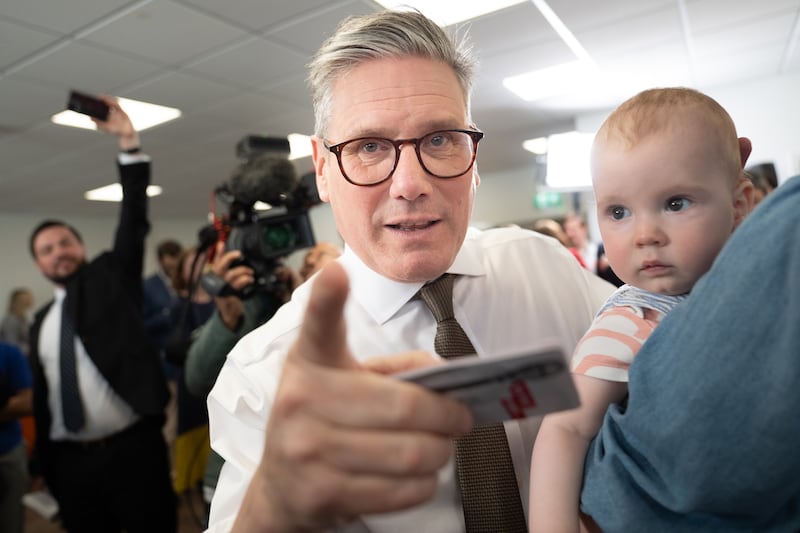 Keir Starmer with a baby at Worcester City Football Club. PA