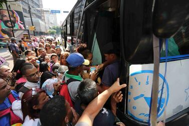 People jockey to enter a bus during a power outage that suspended the subway service in Caracas. AP