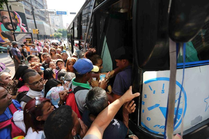 People jockey to enter a bus during a power outage that suspended the subway service in Caracas, Venezuela, Monday, March 25, 2019. (AP Photo/Fernando Llano)