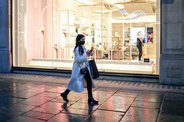 A woman wears a face mask as she walks on London's Regent Street as new Tier-4 restriction measures are announced. AP.