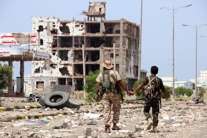 epa07934862 Members of Houthi militia pass a destroyed building during the deployment of observers on cross-lines in Hodeidah, Yemen, 19 October 2019. According to reports, Lieutenant General of India Abhijit Guha, chair of the UN's redeployment coordination committee in the Yemeni city of Hodeidah, oversaw the deployment of observers on cross-lines and checkpoints in Hodeidah to stabilize the ceasefire and activate a new procedure for de-escalation in the port city between the Houthi rebels and the Saudi-backed government forcers. Hodeidah is the key lifeline entry point for most of the Arab country’s food imports and humanitarian aid.  EPA/NAJEEB ALMAHBOOBI