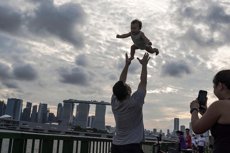 A man throws a young child into the air at a seaside park in Singapore. EPA