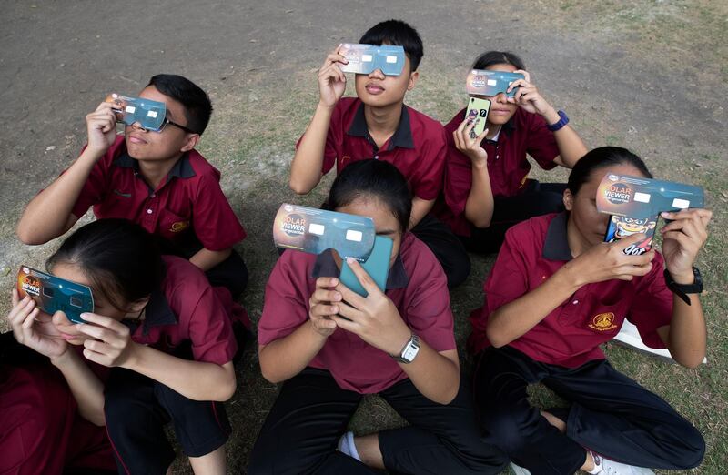 Students hold special filters to watch a solar eclipse from the Santiratwitthayalai School in Bangkok, Thailand.  AP