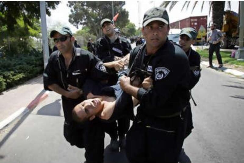 A protester is carried away by Israeli police officers during the "ethnic cleansing" of settlers from the Gaza Strip in August 2005.