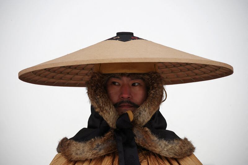 An employee in Korean traditional costume works as it snows on a cold winter day at Gyeongbokgung Palace in Seoul, South Korea. Reuters
