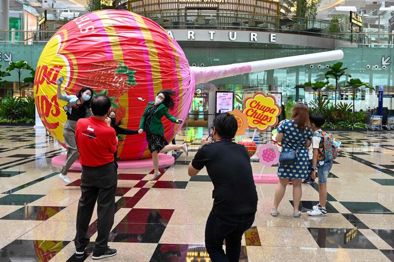 People pose for pictures in front a giant lollipop in the departure hall of Changi International Airport in Singapore. AFP