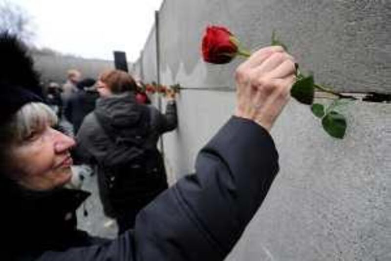 A woman places flowers in the back wall (east side, looking west) of a preserved segment of the Berlin wall during a commemorative event to mark the 20th anniversary of the fall of the wall in Berlin November 9, 2009. AFP PHOTO JOHN MACDOUGALL *** Local Caption ***  205446-01-08.jpg *** Local Caption ***  205446-01-08.jpg
