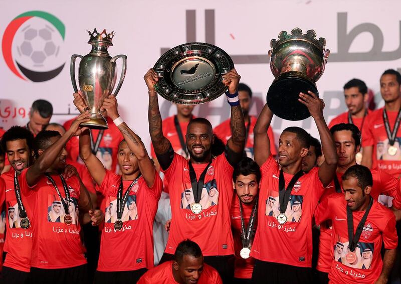 Al Ahli players lift the Arabian Gulf League trophy, centre, following their final match of the season on Sunday. They also display their League Cup trophy, right, and their Super Cup trophy, left. Ahli finished off their domestic season by beating Al Dahfra 5-1 in Dubai. Satish Kumar / The National / May 11, 2014 