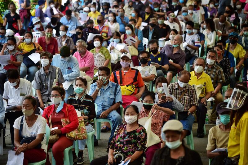 People wearing face masks sit on chairs as they queue to file complaints for not yet receiving the 5,000 Thai baht (150 USD) financial assistance for those whose income is impacted by the COVID-19 coronavirus outbreak, in front of the Public Relations Department in Bangkok on May 7, 2020. / AFP / Lillian SUWANRUMPHA
