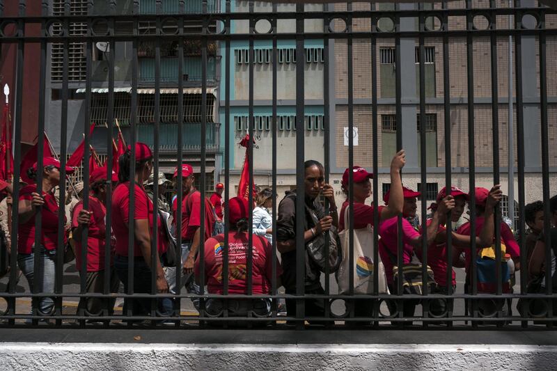Pro-government supporters stand behind a fence during a rally outside of Miraflores Palace in Caracas, Venezuela. Bloomberg