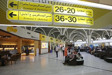 Passengers wearing protective masks wait for flights at the departure hall of Baghdad international airport. AFP